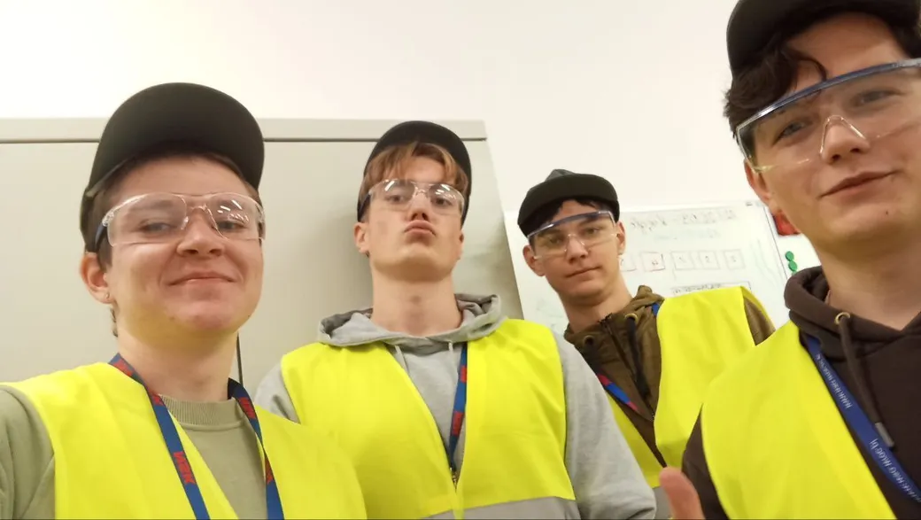 Czterech uczniów na praktykach w kamizelkach ostrzegawczych i okularach ochronnych